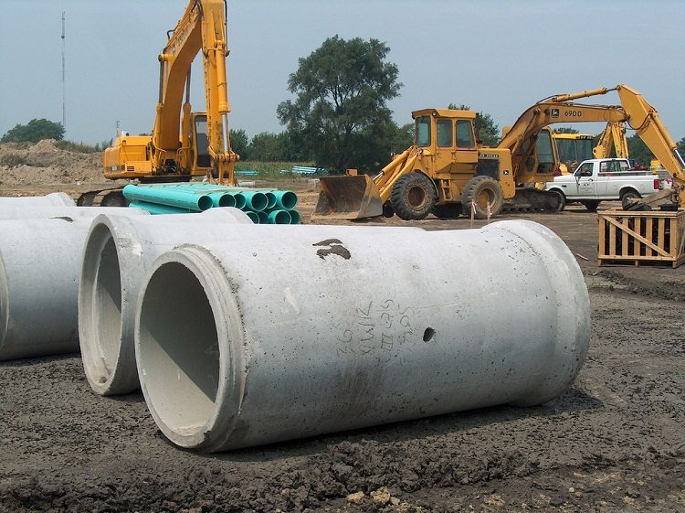 Les tuyaux en béton armé sont très durables, mais les travaux d'installation sont compliqués par le poids élevé de ces produits. Pipe dans un fossé