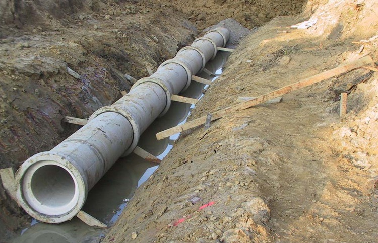 Des tuyaux de prise en béton et en amiante-ciment sont posés à l'avant Trenching