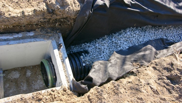 Des tuyaux, des puits, des gravats, du sable et des géotextiles sont nécessaires pour l'installation d'un système de drainage Installation du tuyau de vidange